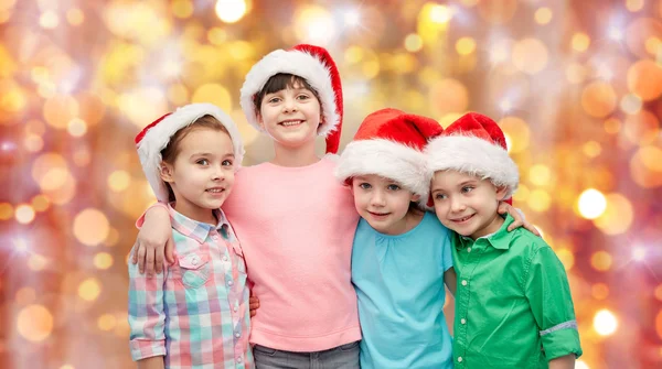 Gelukkig lieve kinderen in santa hoeden knuffelen — Stockfoto
