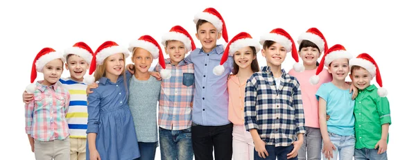 Glücklich lächelnde Kinder in Weihnachtsmützen, die sich umarmen — Stockfoto