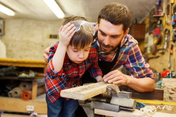 Padre e hijo pequeño con tablón de madera en el taller —  Fotos de Stock