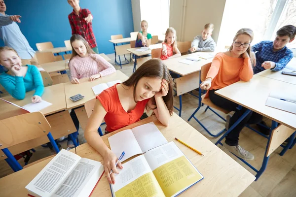 Estudiantes chismorreando detrás de su compañero de clase en la escuela —  Fotos de Stock