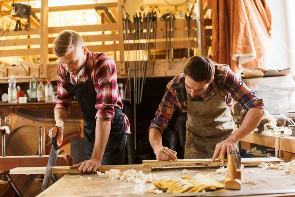 Carpenters working with saw and wood at workshop — Stock Photo, Image
