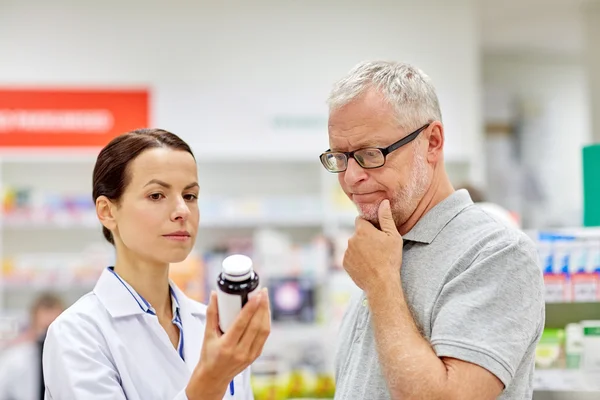 Farmacista che mostra droga all'uomo anziano in farmacia — Foto Stock