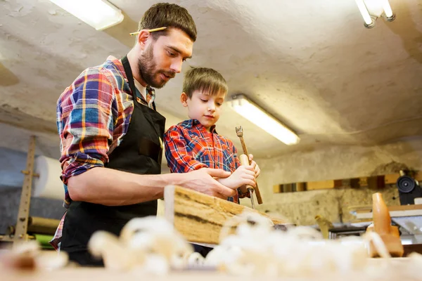 Father and son with chisel working at workshop — Stock Photo, Image