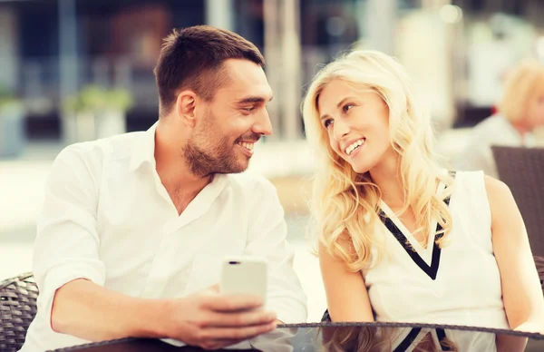 Happy couple with smatphone at city street cafe Royalty Free Stock Images