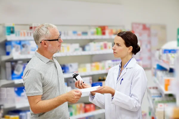 Фармацевт и пожилой человек покупает лекарства в аптеке — стоковое фото