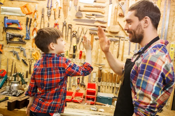 Pai e pequeno filho fazendo alta cinco na oficina — Fotografia de Stock