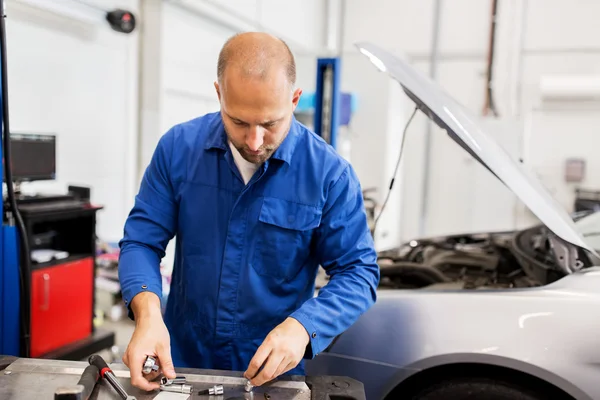 Monteur met moersleutel reparatie auto op de werkplaats — Stockfoto