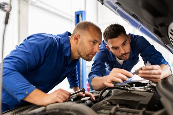 Hombres mecánicos con llave inglesa reparación de coches en el taller — Foto de Stock