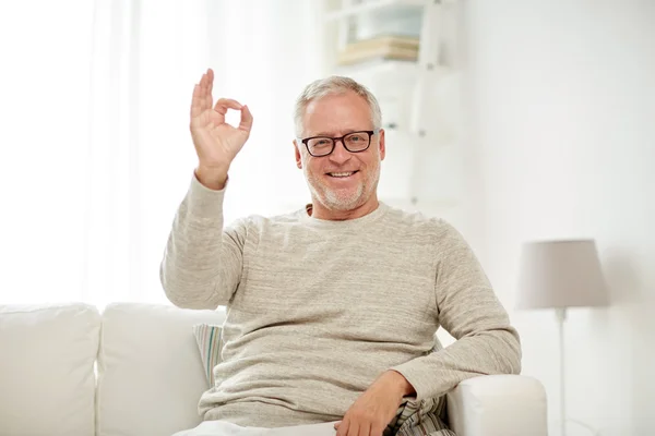 Lächelnder Senior zeigt daheim Handzeichen — Stockfoto
