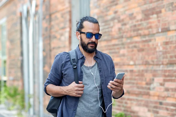 Hombre con auriculares y smartphone caminando en la ciudad — Foto de Stock