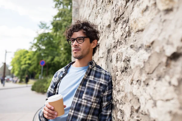 Человек в очках пьет кофе через стену на улице — стоковое фото