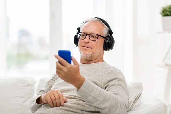 Homem sênior feliz com smartphone e fones de ouvido — Fotografia de Stock