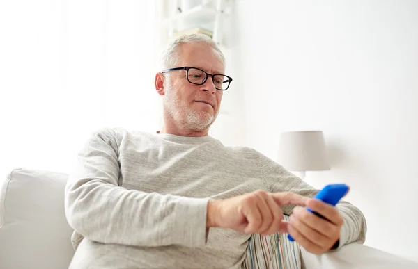Счастливый пожилой человек на смартфоне дома — стоковое фото