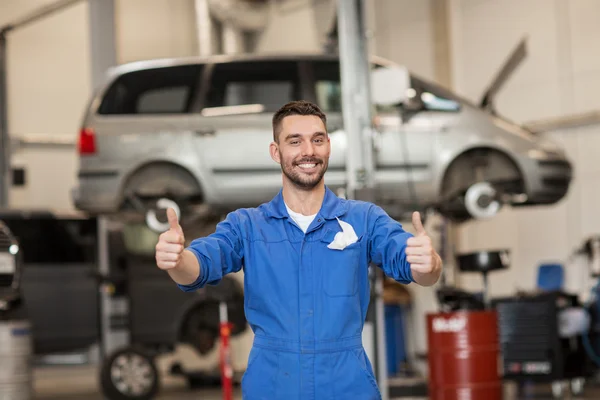 happy auto mechanic man or smith at car workshop