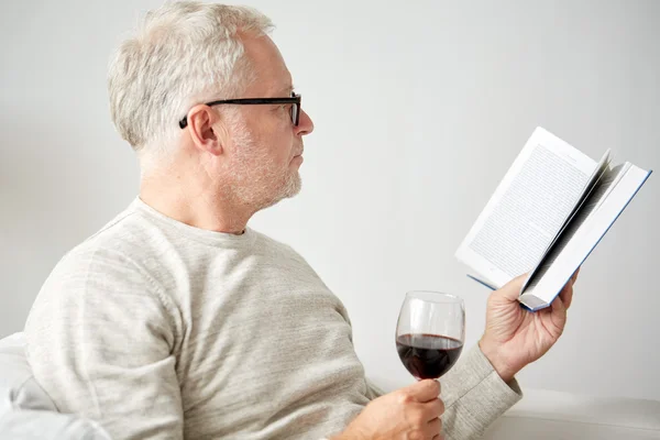 Γηραιότερος άνθρωπος πίνοντας κρασί και διαβάζοντας βιβλίο — Φωτογραφία Αρχείου