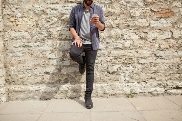 Крупним планом чоловік зі смартфоном на кам'яній стіні — стокове фото