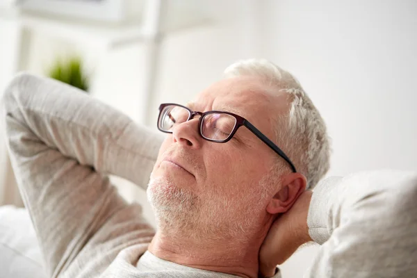 Старший мужчина в очках расслабляется на диване — стоковое фото