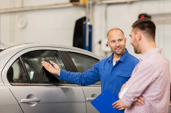 Automechaniker mit Klemmbrett und Mann im Autohaus — Stockfoto