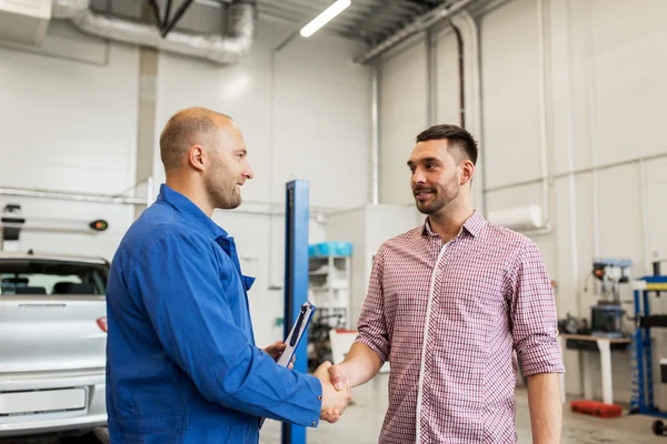 Bilmekaniker och man skakar hand på bil shop — Stockfoto