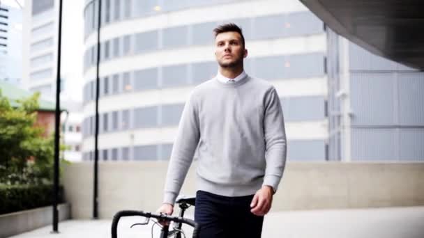 Genç adam şehir bisiklet ile sokak boyunca yürüyüş — Stok video