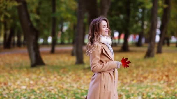 Hermosa mujer joven caminando en el parque de otoño — Vídeo de stock