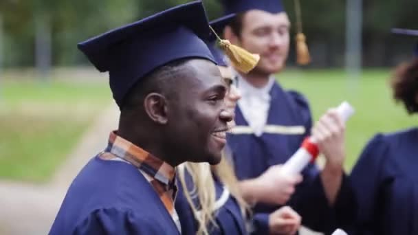 Estudiantes felices en morteros con diplomas — Vídeo de stock