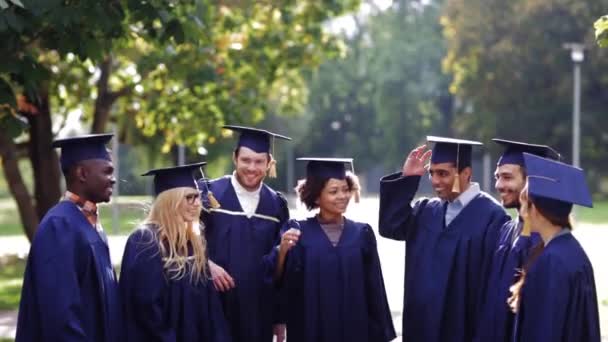 Estudantes felizes jogando placas de argamassa para cima — Vídeo de Stock