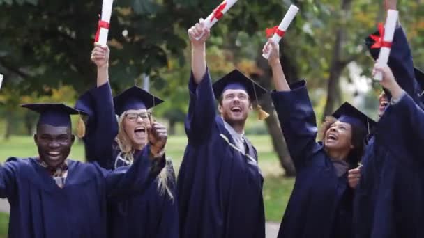 Šťastní studenti v minometných tabulích s diplomy — Stock video