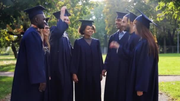 Estudantes felizes em placas de argamassa fazendo alta cinco — Vídeo de Stock