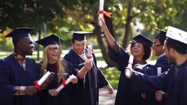 Šťastní studenti v minometných tabulích s diplomy — Stock video