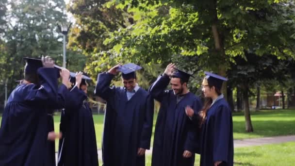 Estudantes felizes jogando placas de argamassa para cima — Vídeo de Stock