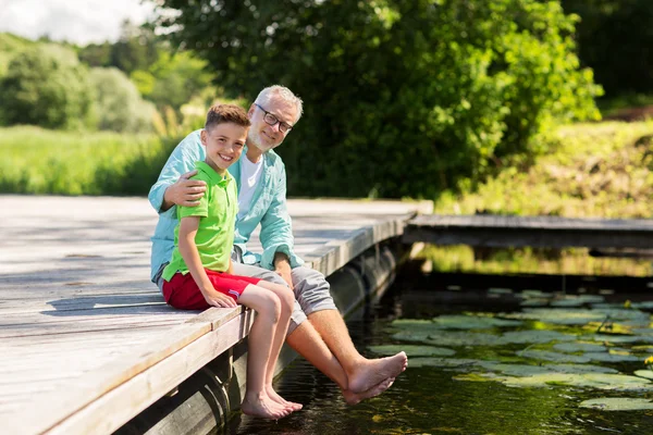Grand-père et petit-fils assis sur le quai de la rivière — Photo