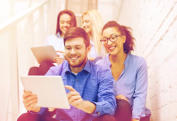 Team with tablet pc computer sitting on staircase — Stock Photo, Image