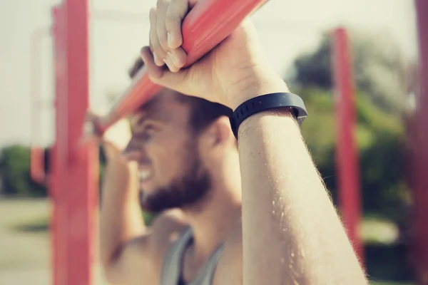 Joven ejercitándose en barra horizontal al aire libre —  Fotos de Stock