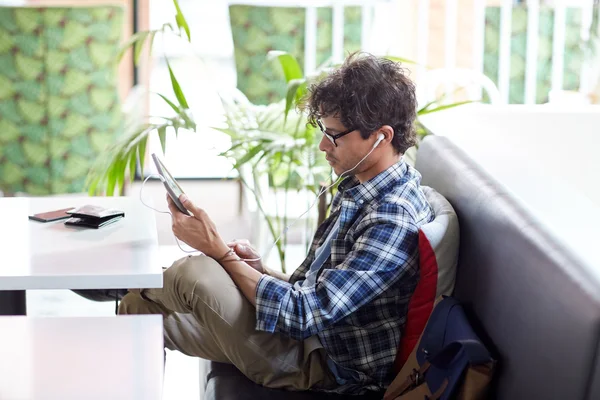 Homme avec tablette PC et écouteurs assis au café — Photo