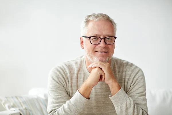 Sonriente hombre mayor en gafas sentado en el sofá — Foto de Stock