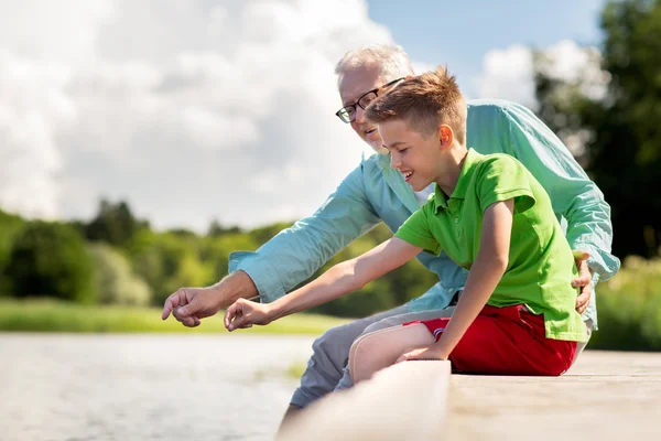 Grandfather and grandson sitting on river berth — Stock Photo, Image