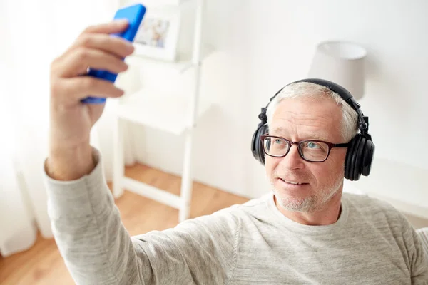 Старший человек со смартфоном и наушниками — стоковое фото