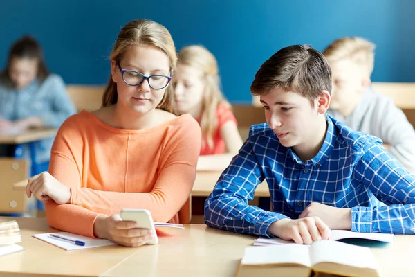 Estudiantes con mensajes de texto de teléfonos inteligentes en la escuela — Foto de Stock