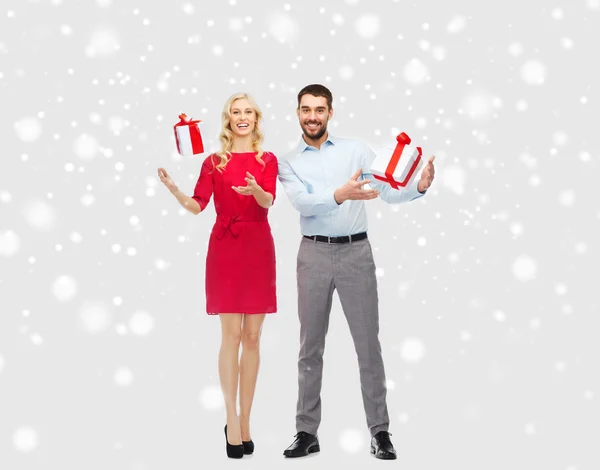 Glückliches Paar mit Weihnachtsgeschenkschachteln über Schnee — Stockfoto