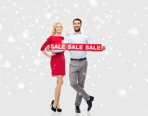 Щаслива пара з червоним знаком продажу над снігом — стокове фото