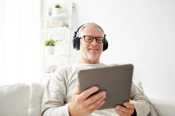 平板电脑和耳机在家里的老人 — 图库照片