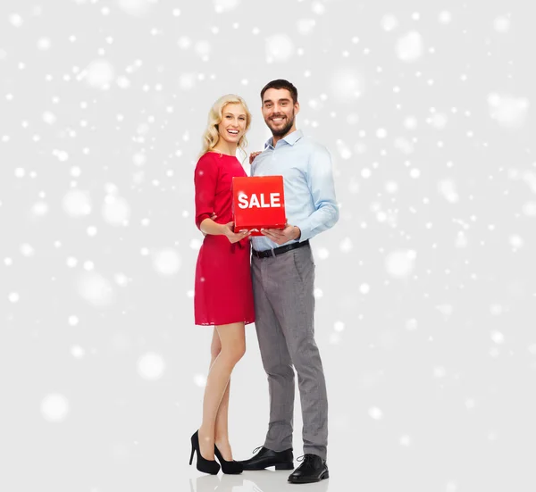 Feliz pareja con venta roja signo sobre la nieve — Foto de Stock