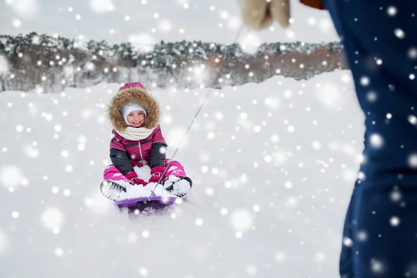 Rodziców, prowadzenie szczęśliwe małe dziecko na sankach zimą — Zdjęcie stockowe