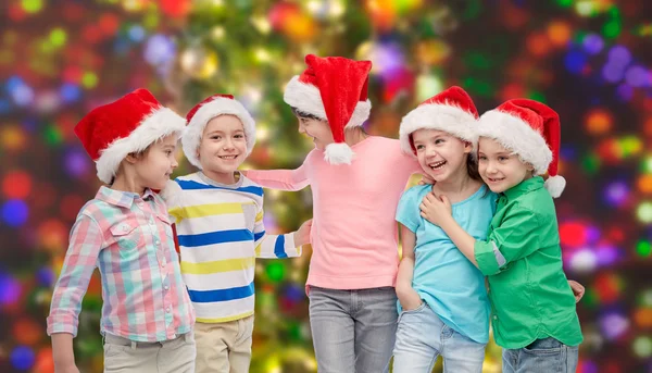 Niños pequeños y felices en sombreros de santa abrazo —  Fotos de Stock