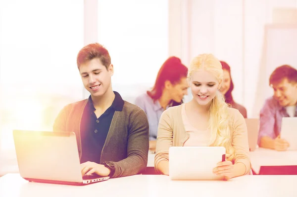 Dos estudiantes sonrientes con ordenador portátil y tableta PC —  Fotos de Stock