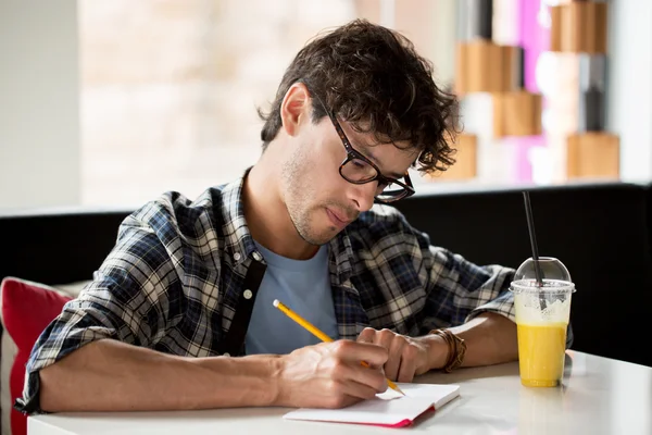 Muž s Poznámkový blok a šťáva psaní v kavárně — Stock fotografie