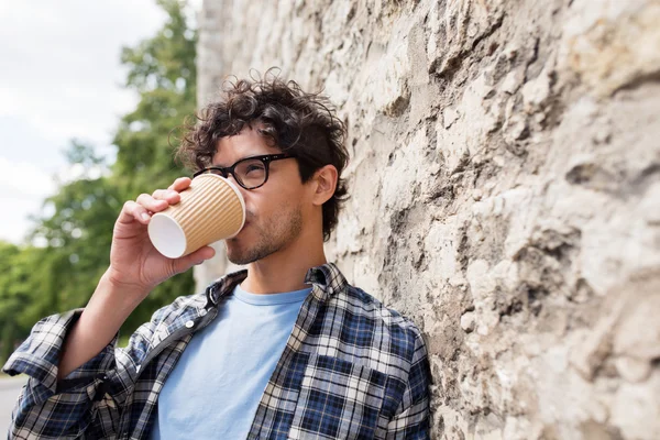 Hombre con anteojos bebiendo café sobre la pared de la calle —  Fotos de Stock