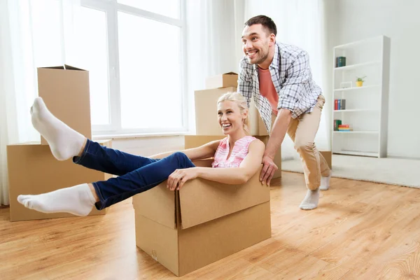 Pareja con cajas de cartón que se divierten en un nuevo hogar — Foto de Stock