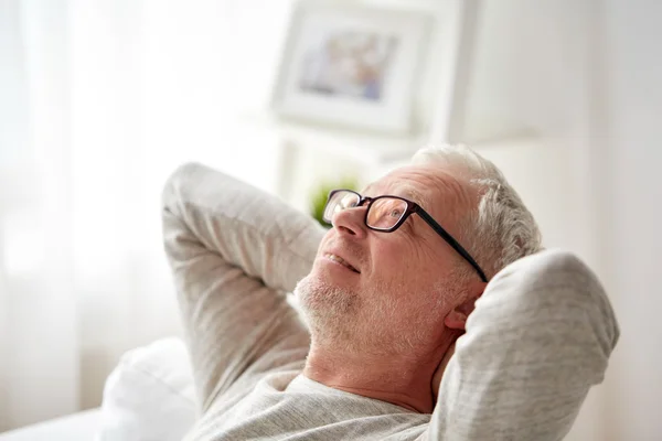 Улыбающийся мужчина в очках расслабляется на диване — стоковое фото